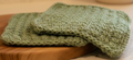 2 handmade crocheted green washcloths.